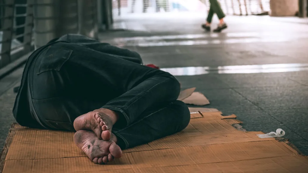 close up feet homeless man sleeping dirty floor urban street city